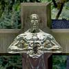 A gold statue standing perfectly in line with a wooden cross right behind it.