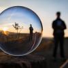  A bubble reflecting the image of a person standing in a desert landscape with a sunset behind them