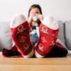 Woman sitting on couch wearing red Christmas socks propped up on table holding mug
