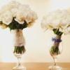 Two bouquets of white roses in glass vases on table