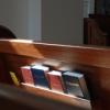 Empty pew with Bibles and hymnbooks in rack