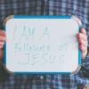 Man holding whiteboard that says "I am a Follower of Jesus"