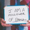 Man holding whiteboard that says "I am a Follower of Jesus"