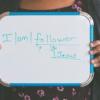 Woman holding whiteboard that says "I am a Follower of Jesus"