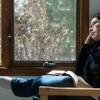 a woman with a Bible on her lap looking through a window
