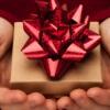 a cupped pair of hands holding a small box with a bow on it.