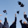 Group of graduates in gowns throwing caps up into air in celebration