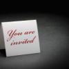 folded white paper that stands up and says "you are invited" in red letters