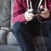 Jesus action figure standing on top of video game controller next to a person playing video games