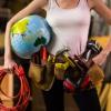 a woman wearing a tool belt and holding an inflatable globe under her arm