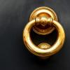 a gold door knocker on a black door