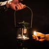 a person lighting a lantern in the dark.