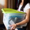 Woman carrying plastic tub of things into room