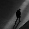 Black and white image of man walking alone