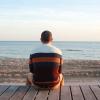 Man seated on boardwalk staring at ocean