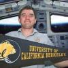 Rex Walheim holding a University of California, Berkeley Banner in space shuttle cockpit