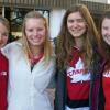 Group of four young female students arm in arm smiling outside of dorm