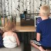 three small children sitting at a countertop using a computer