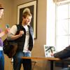 Male and female student walking up to campus minister at table with computer