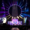 Stage of Urbana with huge ring of colorful lights, bright stage pieces, and shadowy background 