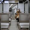 a woman wearing a mask sitting alone on a train